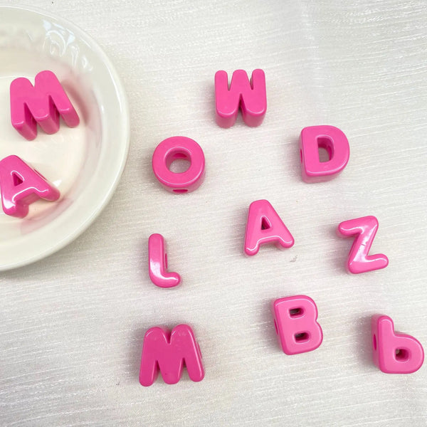 Perles de lettres acryliques roses formant le mot MOWLAZ et des lettres individuelles comme L, A, Z, B.