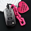 A silver car key fob attached to a bright pink chain, next to a pink heart-shaped tag.