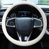 A close-up view of a steering wheel covered with a light beige silicone anti-slip cover inside a car