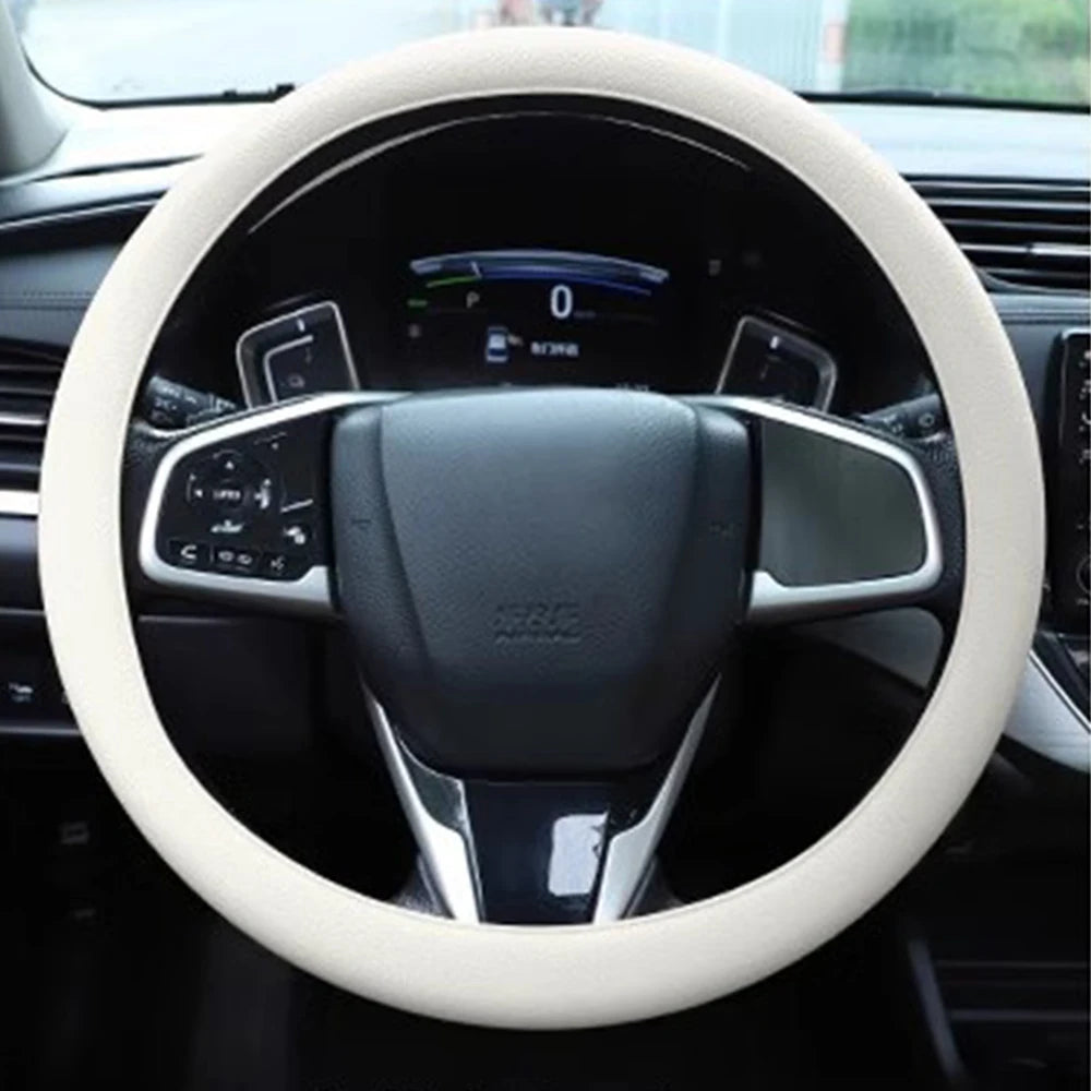 A close-up view of a steering wheel covered with a light beige silicone anti-slip cover inside a car