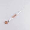 A brown silicone pacifier clip with a white floral design and a gold lanyard attached.
