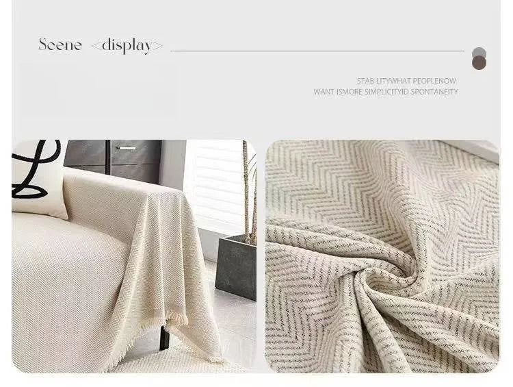 A close-up of an elegant beige herringbone chenille sofa throw with tassel edges draped on a light-colored surface.