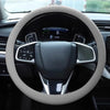 A close-up view of a steering wheel with a light gray silicone cover installed inside a car interior.