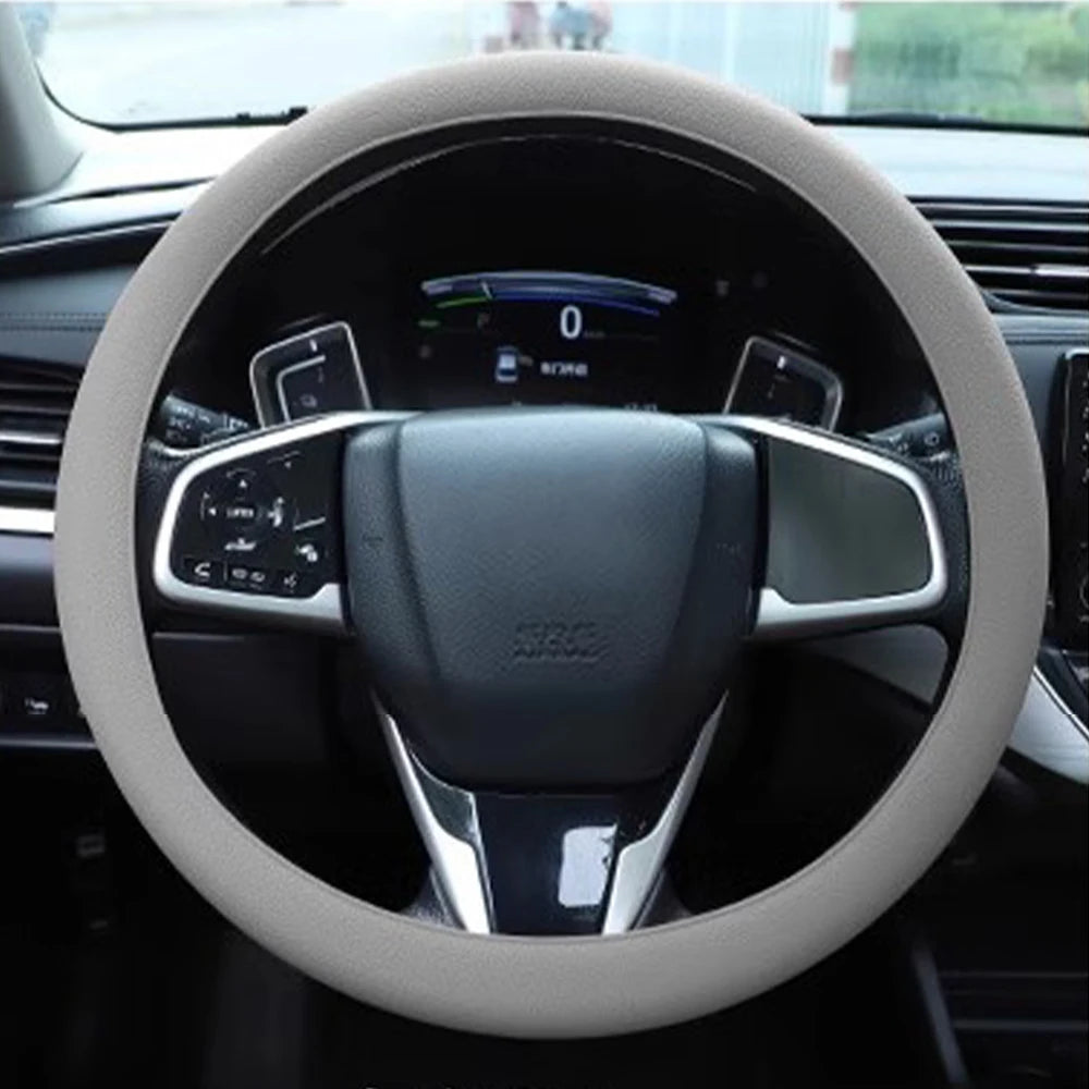 A close-up view of a steering wheel with a light gray silicone cover installed inside a car interior.
