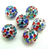 A collection of colorful crystal clay round beads in various shades of blue, green, and red scattered on a white surface.