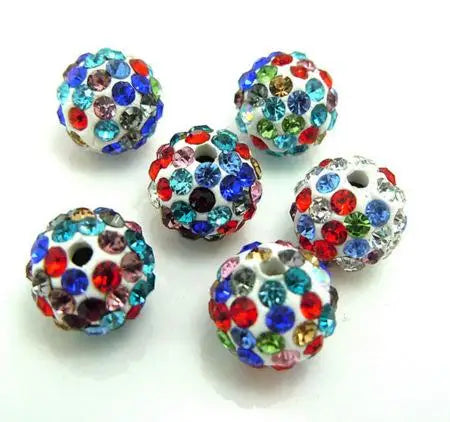A collection of colorful crystal clay round beads in various shades of blue, green, and red scattered on a white surface.