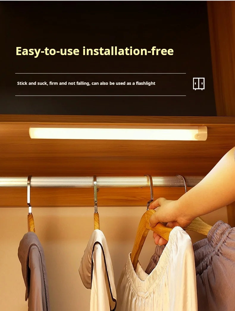 A hand is hanging a stick and puck-like light fixture on a wooden cabinet shelf.