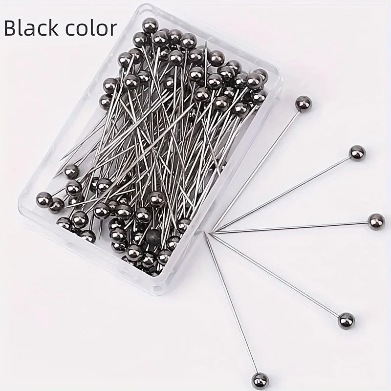 A clear plastic container filled with 100 black precision quilting pins for sewing and crafting.
