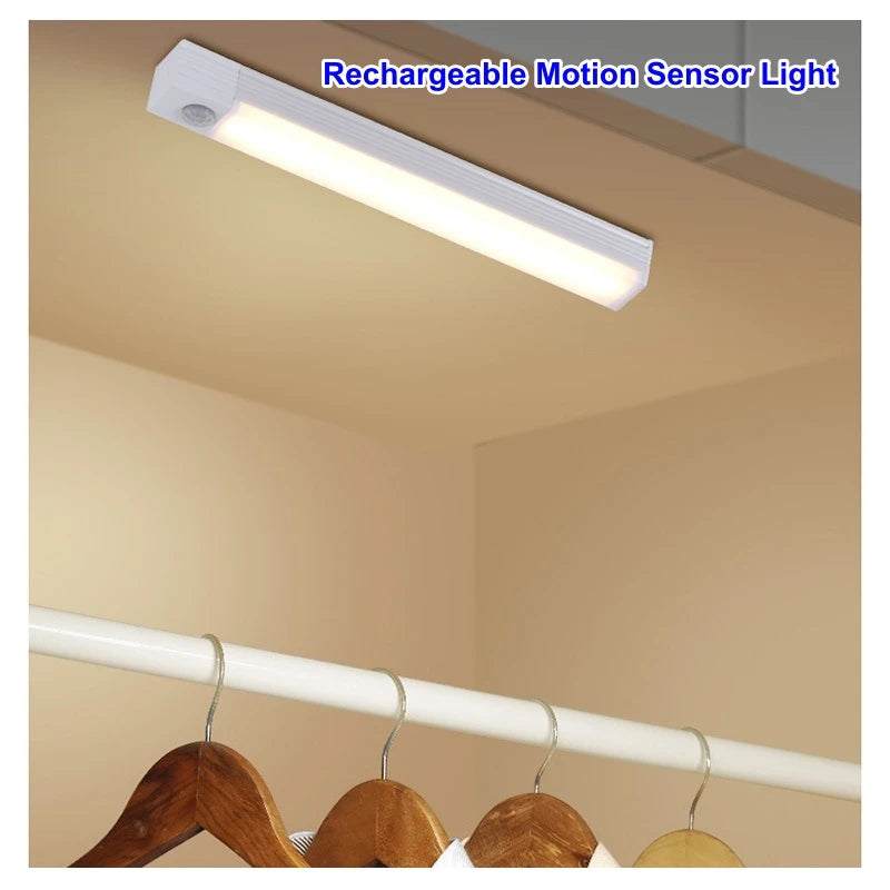 A white rechargeable motion sensor light bar mounted on a ceiling, with wooden hangers visible below.