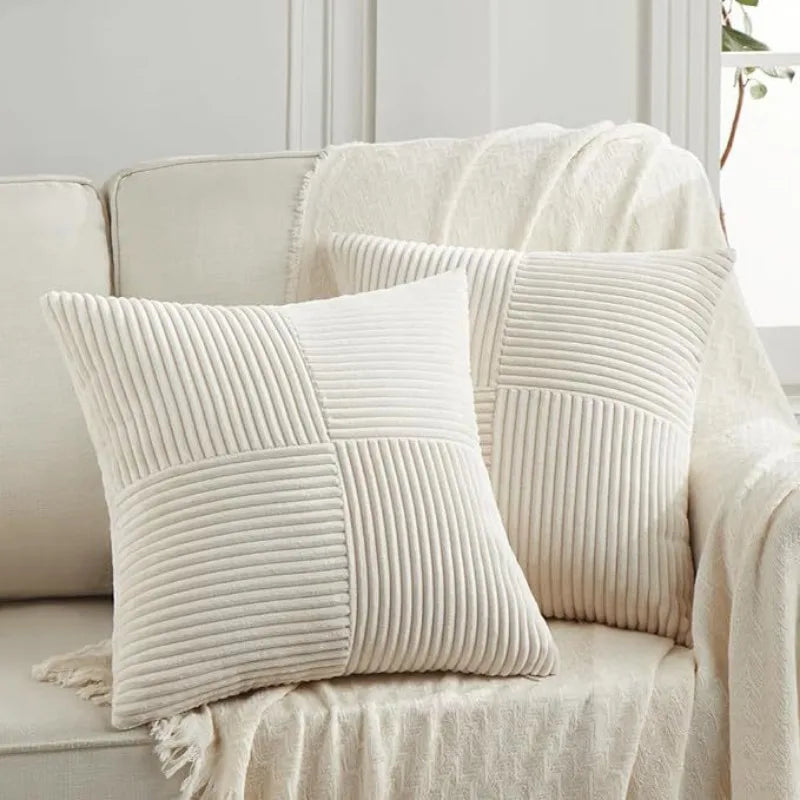 Two cream-colored, vertically ribbed patchwork throw pillow covers resting on a light beige sofa.