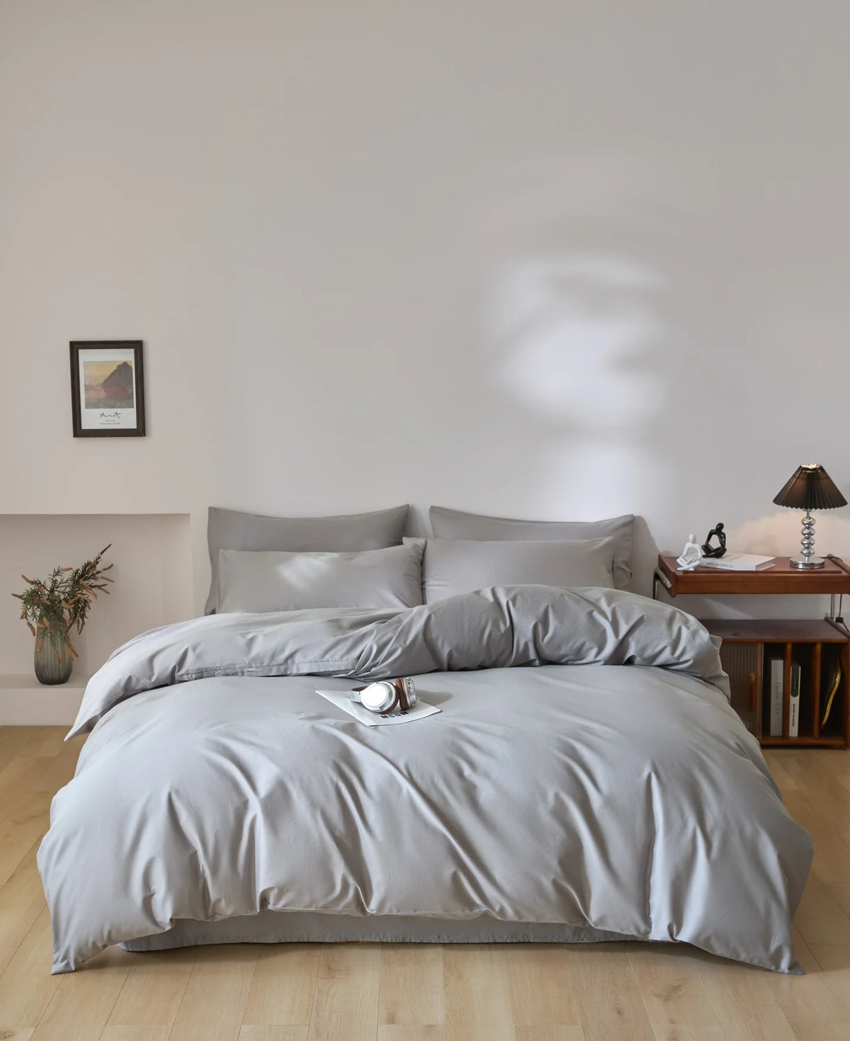 A light gray quilted duvet cover set with matching pillowcases on a bed in a bright room.