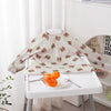 A white table displays a long-sleeve waterproof baby bib with a cute brown animal print for a baby.