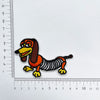 An embroidered patch of a dog's head and body in orange, black, and yellow thread.