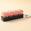 A black LED mechanical keychain fidget toy with pink custom keycaps is displayed on a light background.