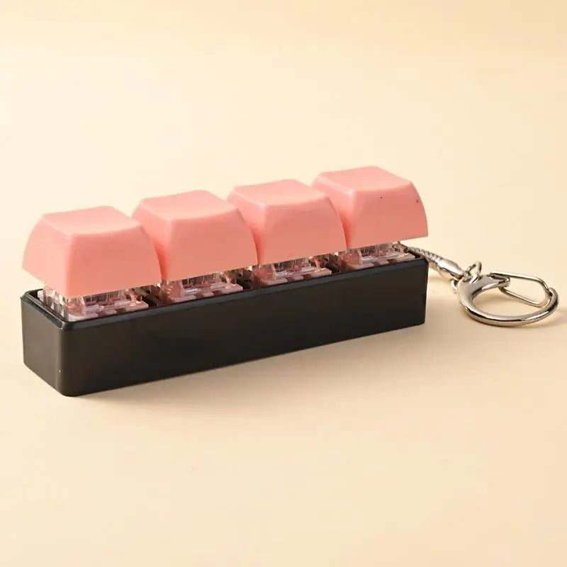 A black LED mechanical keychain fidget toy with pink custom keycaps is displayed on a light background.
