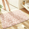 A pink plush non-slip absorbent bathroom rug with a pebble texture placed on a wooden floor.