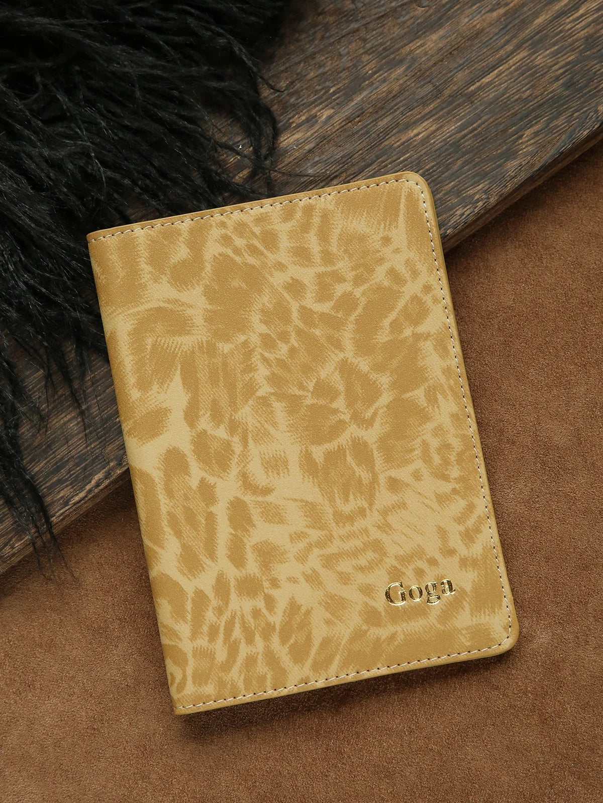 A tan leather passport holder with a leopard print pattern and personalized name embossing rests on a brown surface.