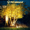 A bright yellow tree is illuminated by a ground spike LED light in a garden setting during the night rain.