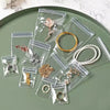 Clear self-sealing jewelry storage bags filled with various gold and silver rings, necklaces, and earrings on a green tray