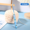 A blue ergonomic crochet hook with a bee design is shown next to a ball of light pink yarn.