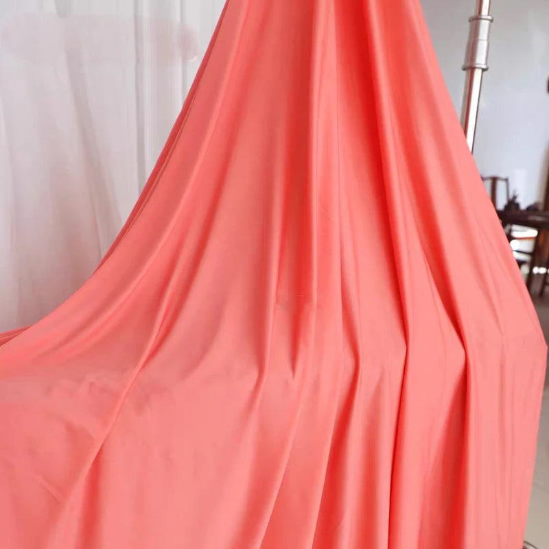 Flowing orange fabric draped in a vertical fold for decor or draping.