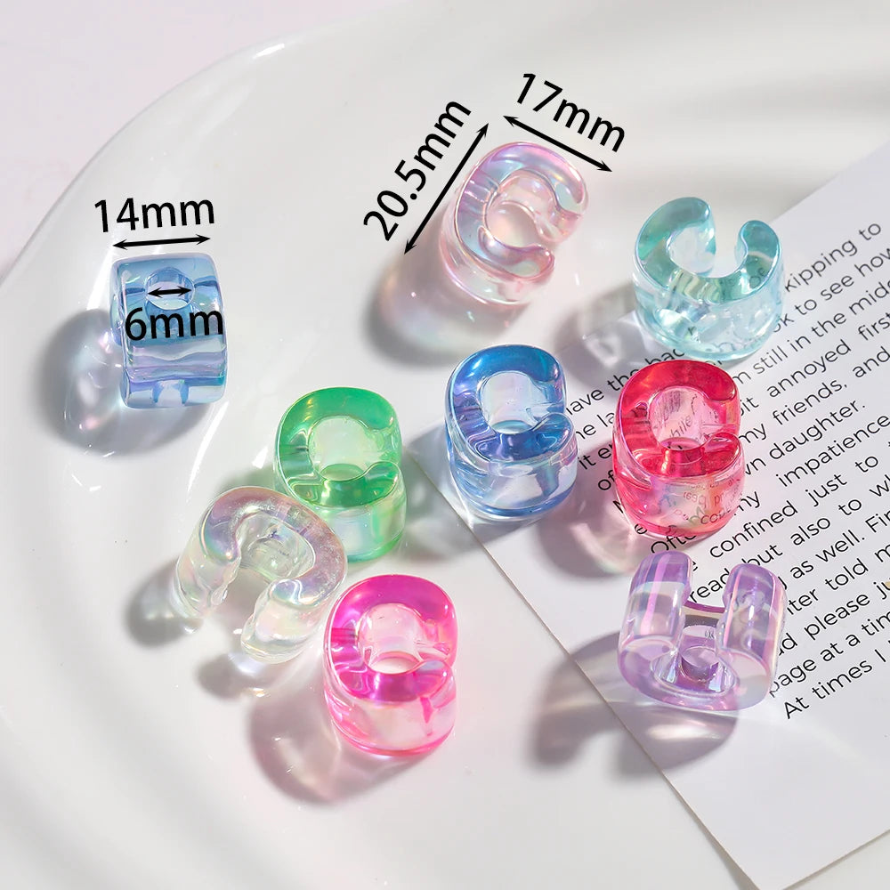 A collection of colorful acrylic alphabet beads and findings displayed on a white plate.