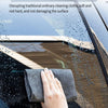 A hand wipes water stains from a car window using a dark gray microfiber cloth.