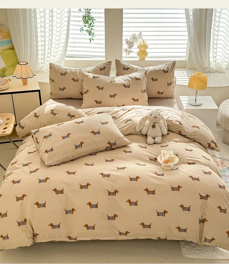 A beige duvet cover set featuring a cute dog print pattern with matching pillowcases and a small stuffed dog toy.