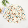 A light-colored waterproof long-sleeve smock for toddlers with a multi-colored polka dot pattern and a front pocket.