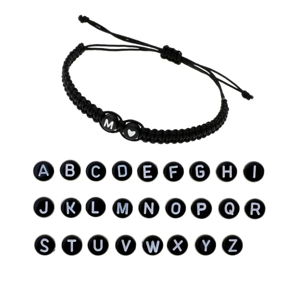 A black beaded bracelet with a heart charm and initial letter for personalization