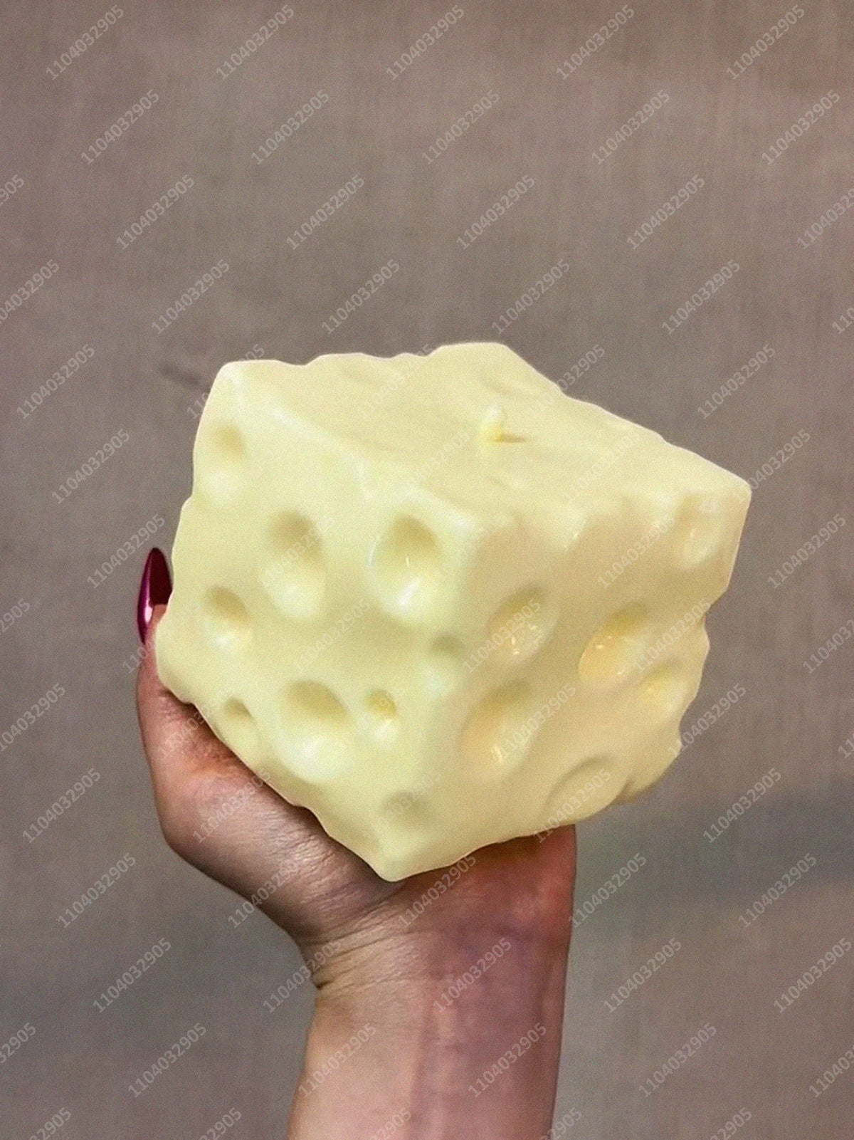 Eine Hand hält einen großen, blassgelben, quetschbaren Stressball-Fidget-Spielzeug vor einem neutralen Hintergrund.