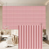 Pink vertical slat wall panels in a modern interior setting with a pink striped wallpaper backdrop.
