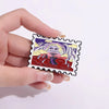 A hand holds a vintage airline ticket enamel brooch featuring a stylized monster design.
