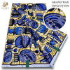 A bolt of blue and yellow African wax print fabric featuring intricate patterns and glitter texture.