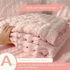 Pink bubble yarn summer cool quilt shown being folded on a bed with a hand