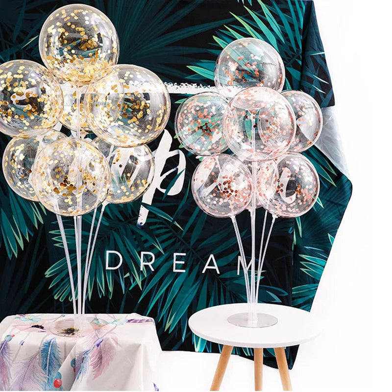 A column of clear plastic balloons with gold glitter accents displayed on a white table.