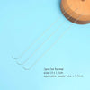 Three curved stainless steel beading needles laid diagonally on a light blue surface.