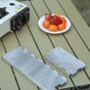 A silver portable aluminum alloy windshield is placed on a wooden table next to some fresh fruit.