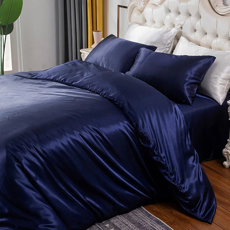 A dark navy blue silky duvet cover set with corner ties and a zipper displayed on a bed.