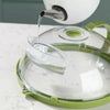 A clear microwave splatter cover with a steamer nozzle and green handle is shown pouring liquid onto a plate.