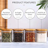 A set of four square glass spice jars with bamboo lids and labels, featuring various dried herbs and spices.