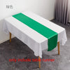 A white tablecloth with a green satin table runner is displayed on a table.