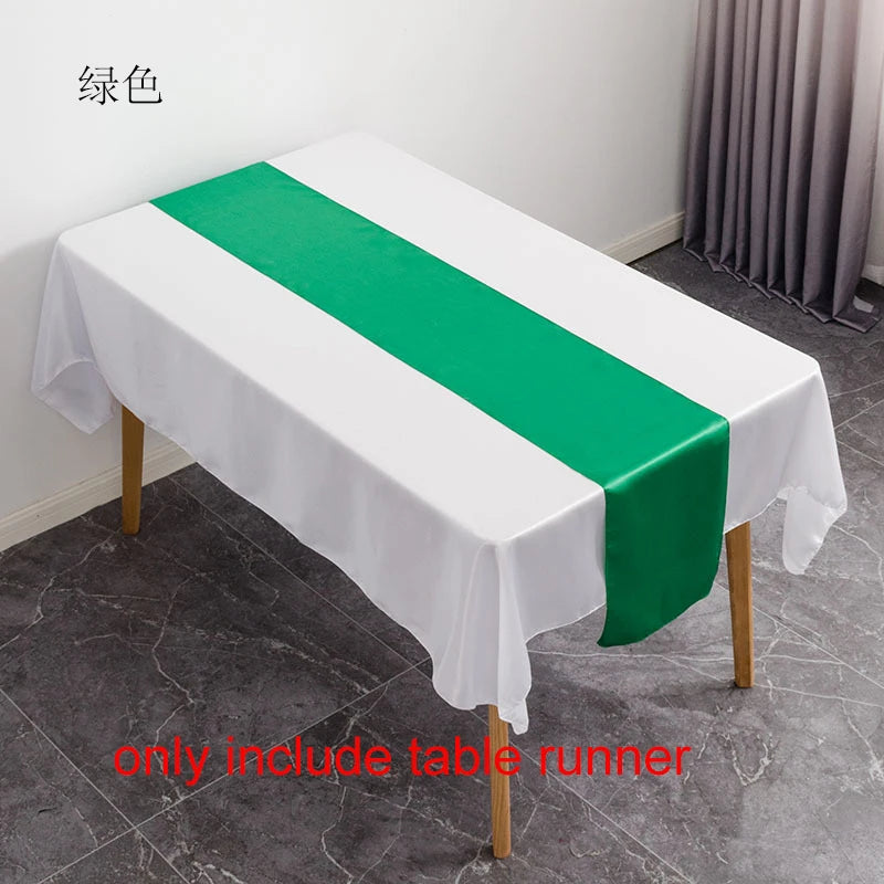 A white tablecloth with a green satin table runner is displayed on a table.