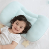 A smiling baby is lying on a light blue breathable pillow with a yellow star accessory.