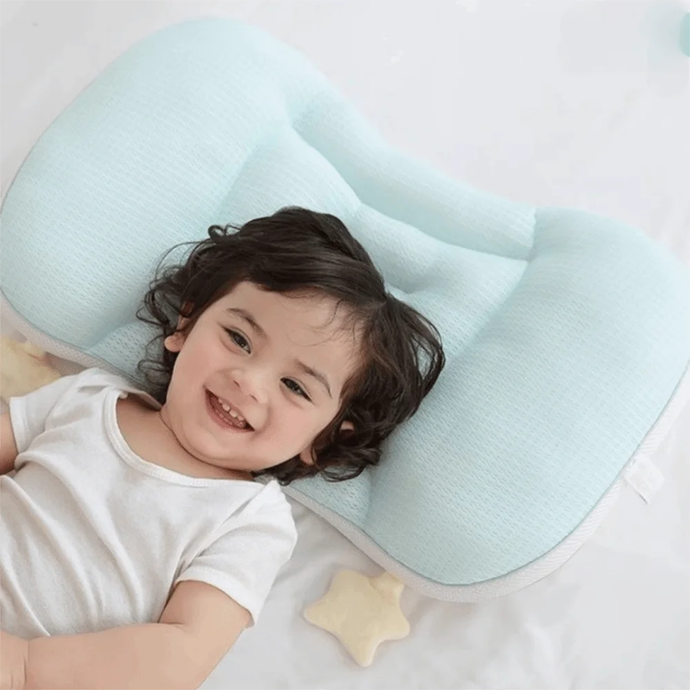 A smiling baby is lying on a light blue breathable pillow with a yellow star accessory.