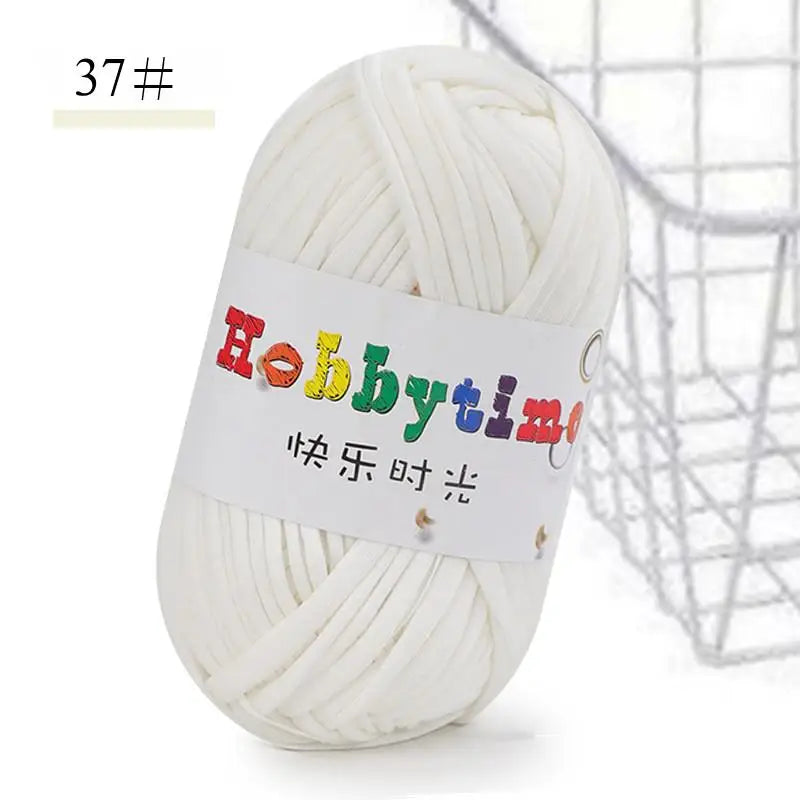 A ball of white soft T-shirt yarn for crochet and knitting is shown next to a wire basket.