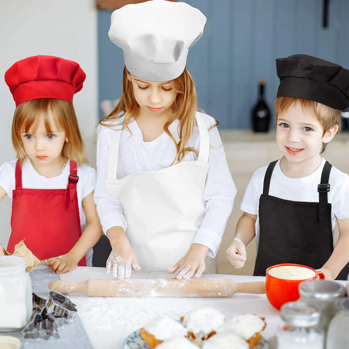 Two children wearing white chef hats and aprons working together on baking ingredients.