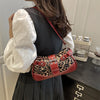 A woman holds a red leopard print PU leather shoulder bag against a dark gray dress.