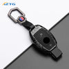 A slim carbon fiber car key cover with a metal clasp and electronic components.