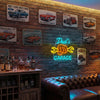 A brick wall decorated with vintage Ford Mustang and Corvette neon signs, featuring a leather couch and wooden shelving.